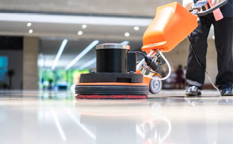Man operating orange floor machine on building floor