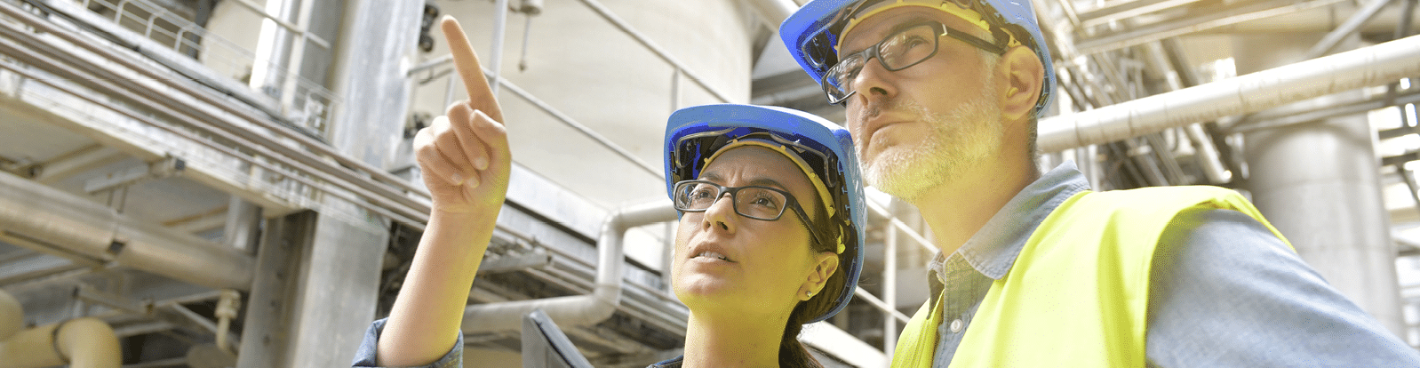 Industrial engineers working in recycling plant with tablet   Network of pipes in the background 