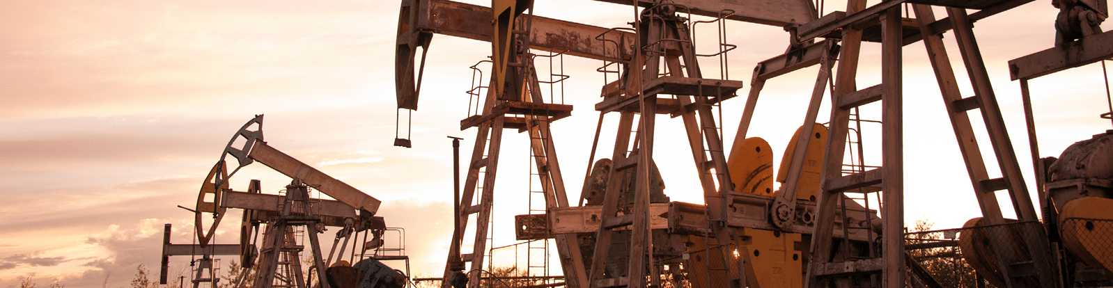 Oil pump jacks at sunset sky background  Toned 