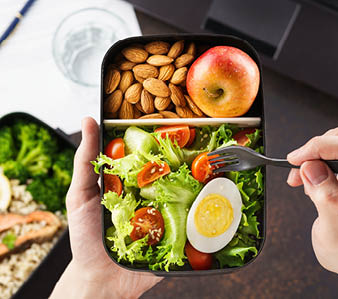 Healthy lunch at office workplace  Man eating nutrition lunch from takeaway lunch box at working table with laptop 