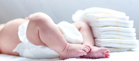 Feet of newborn baby on changing table with diapers  Cute little girl or boy two weeks old  Dry and healthy body and skin concept  Baby nursery