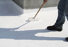 Person applying roof coating with a brush 