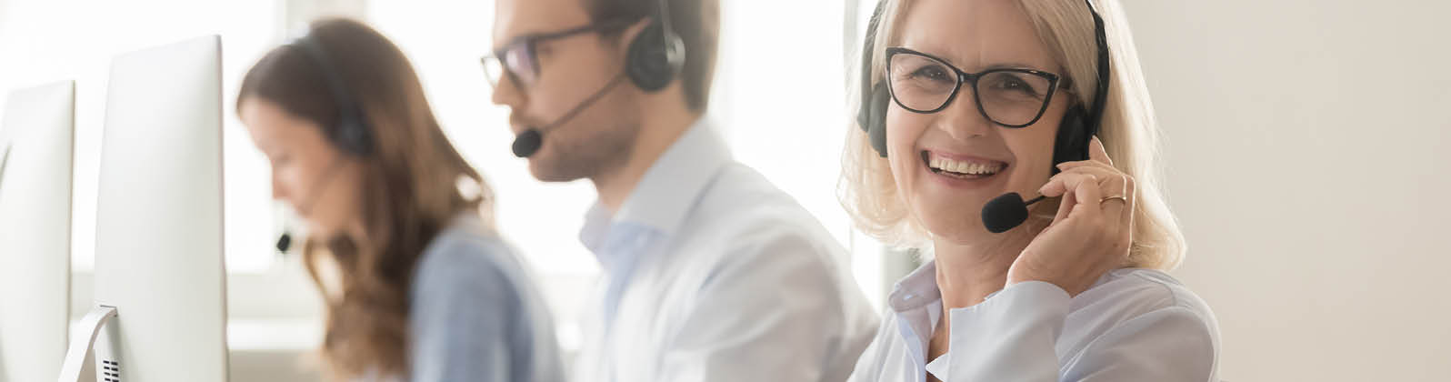 Happy old mature female call center agent telemarketer looking at camera at work, smiling aged woman telesales operator in wireless headset with computer in customer service support office, portrait